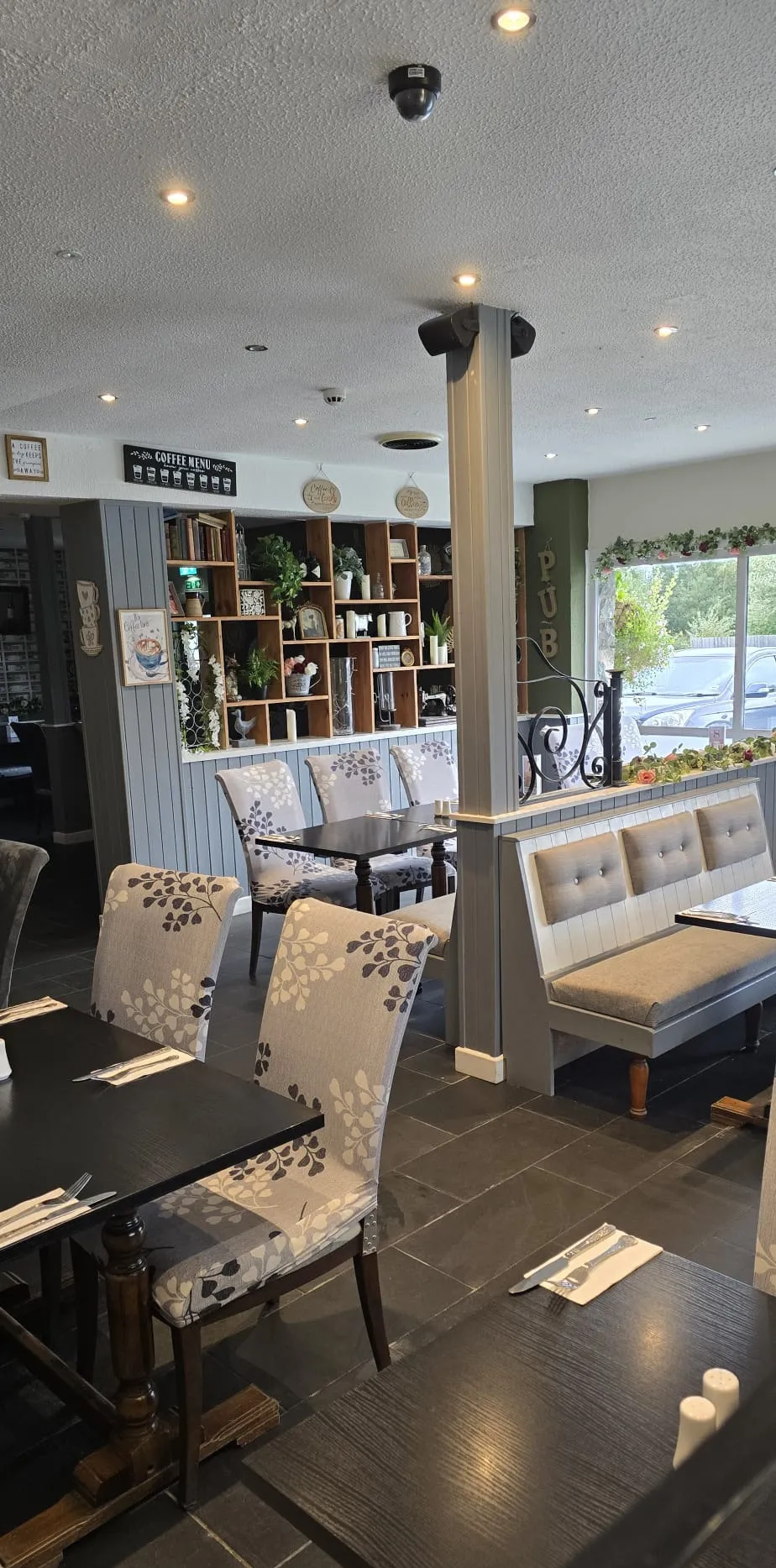 The restaurant: banquette seating and dark tables on a slate floor, daylight from the left