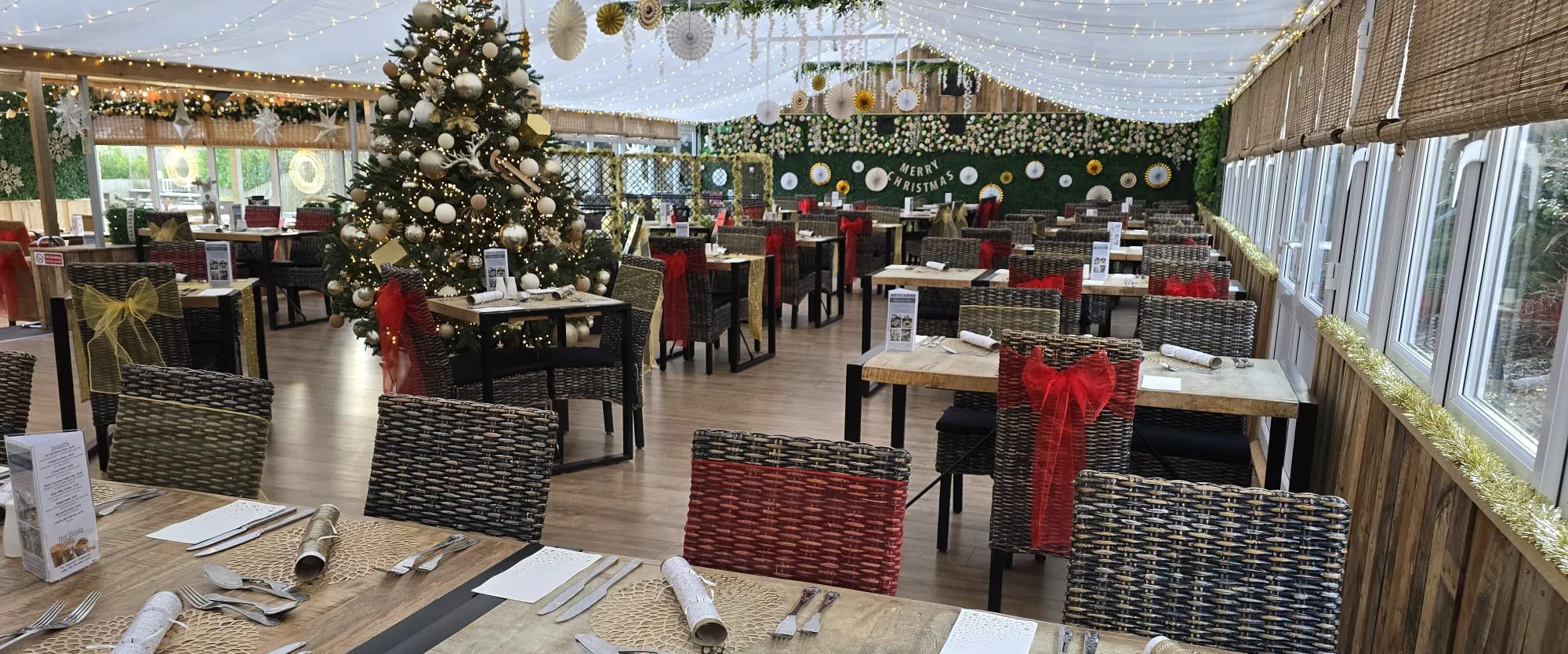 Christmas place settings with crackers and red and gold sashes down the laid tables