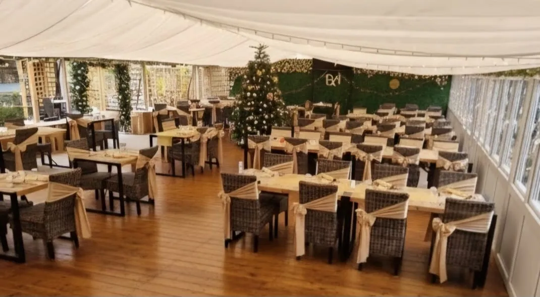 The conservatory set for Christmas Day: tables laid the length of the room, tree at the far end