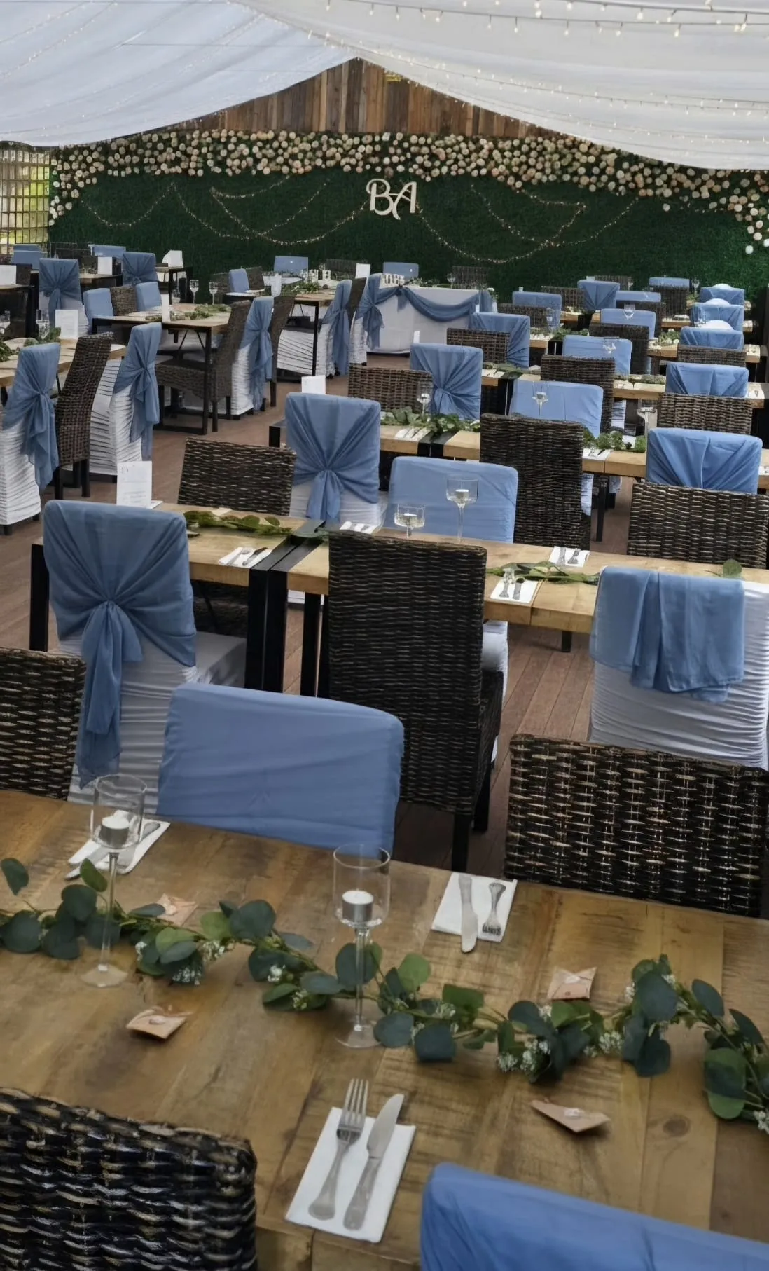 Tables dressed in blue sashes with a eucalyptus runner along the wood