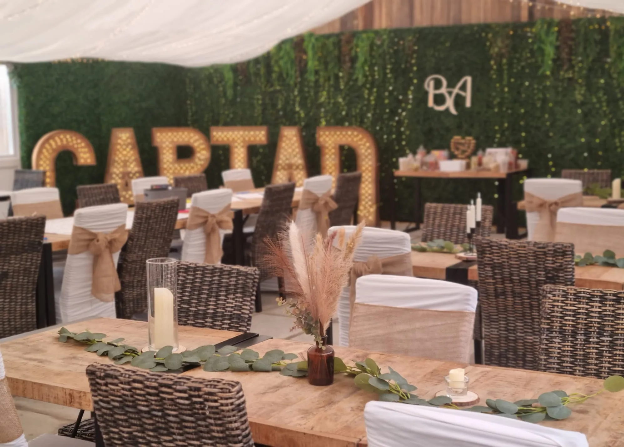 The room dressed with lit CARIAD letters, hessian sashes and a foliage wall
