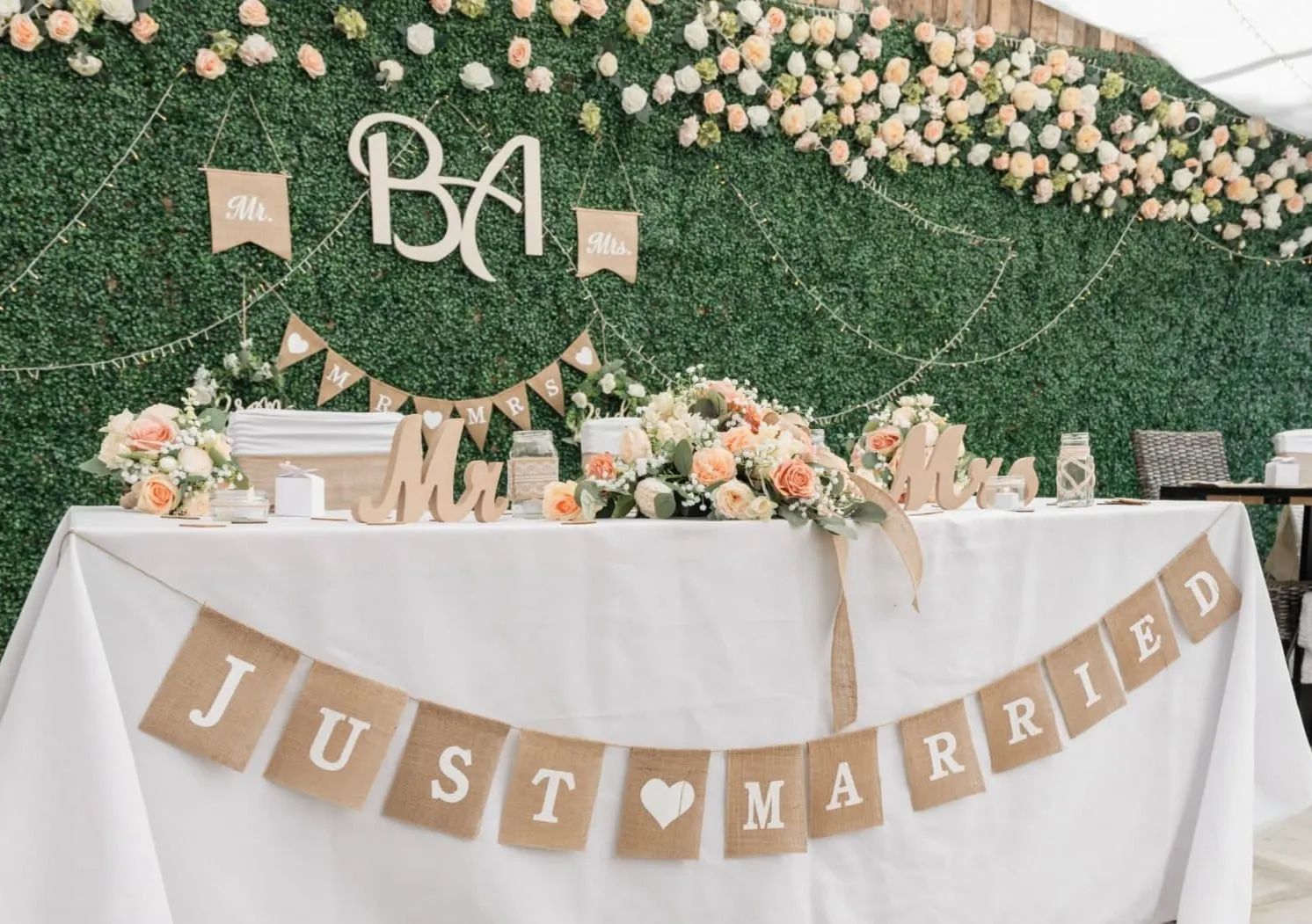 The top table with a JUST MARRIED banner, Mr and Mrs signs and a flower wall