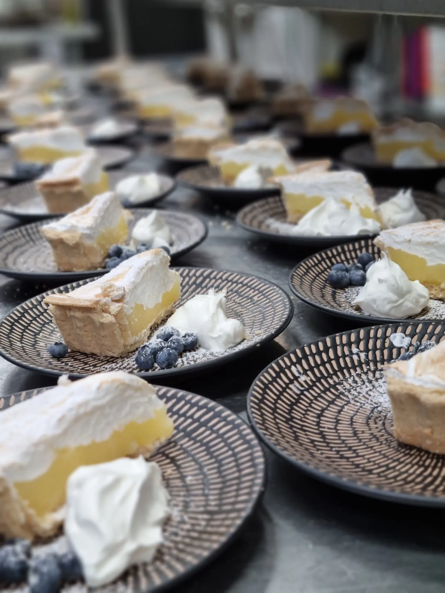 Slices of lemon meringue pie with cream and blueberries, plated up