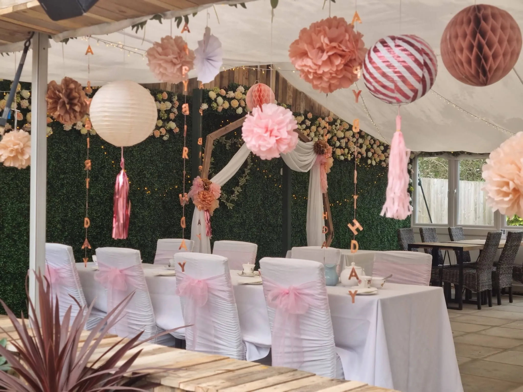 The function space dressed for a party: white tables, paper decorations and a flower arch