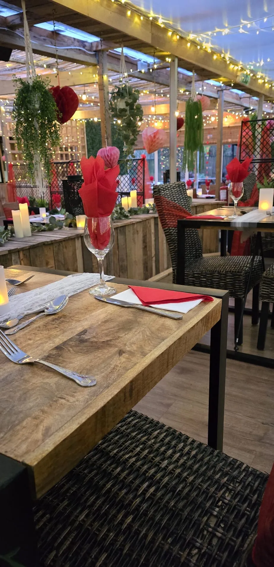 Tables dressed for a Valentine night with red napkins, candles and heart decorations