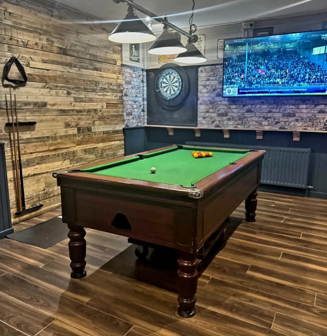 The games nook: the pool table under pendant lights, the dartboard and the big screen behind