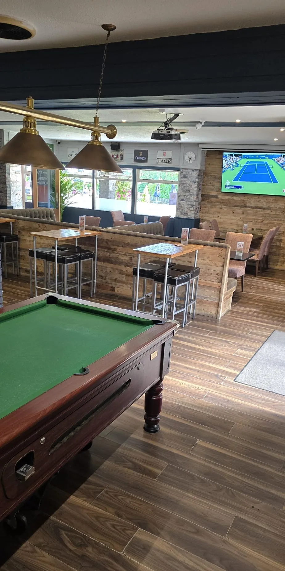 The games end of the pub, with a pool table, high stools and a big screen