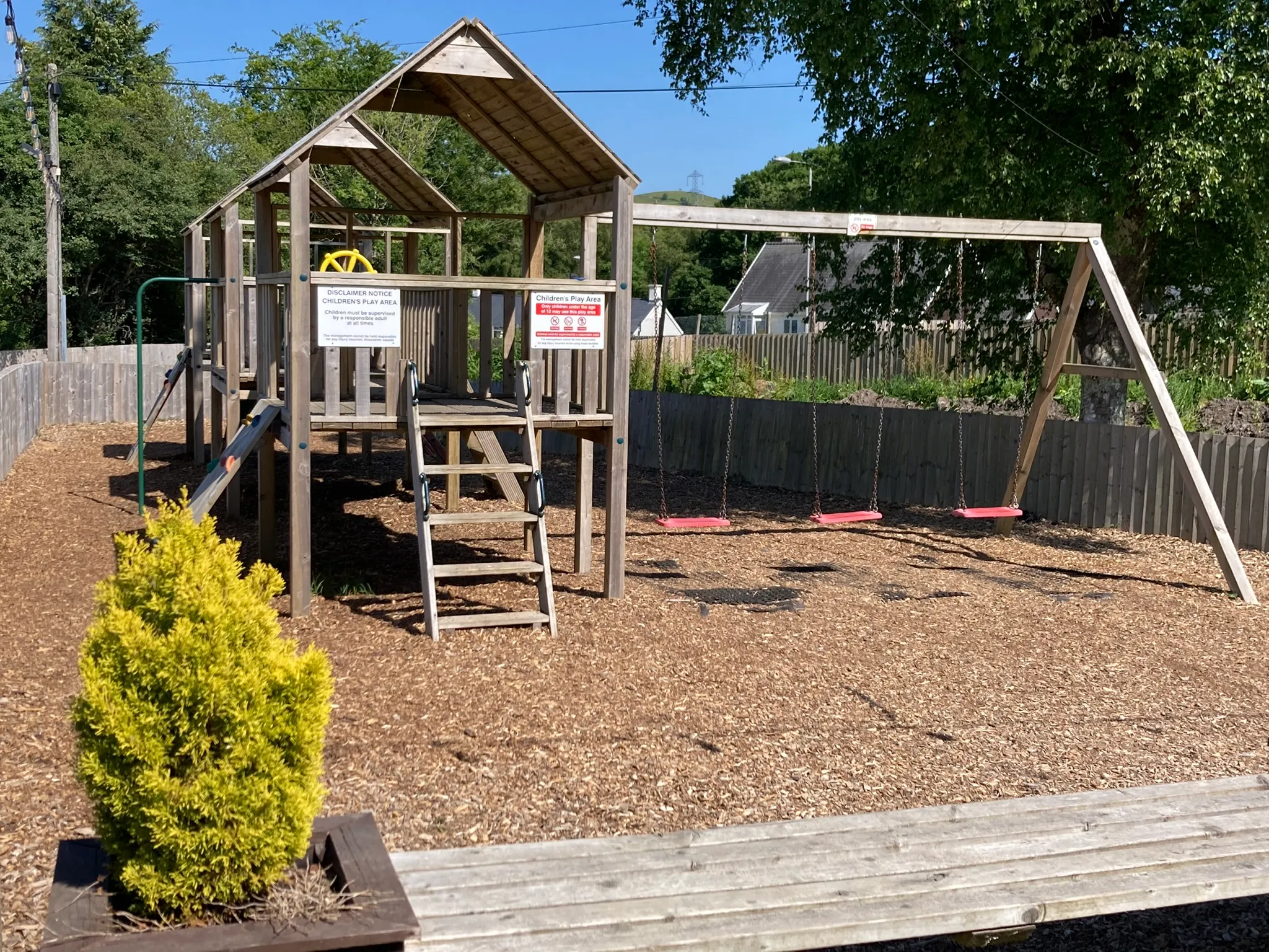 Swings and climbing frames in the play area, on a bark surface