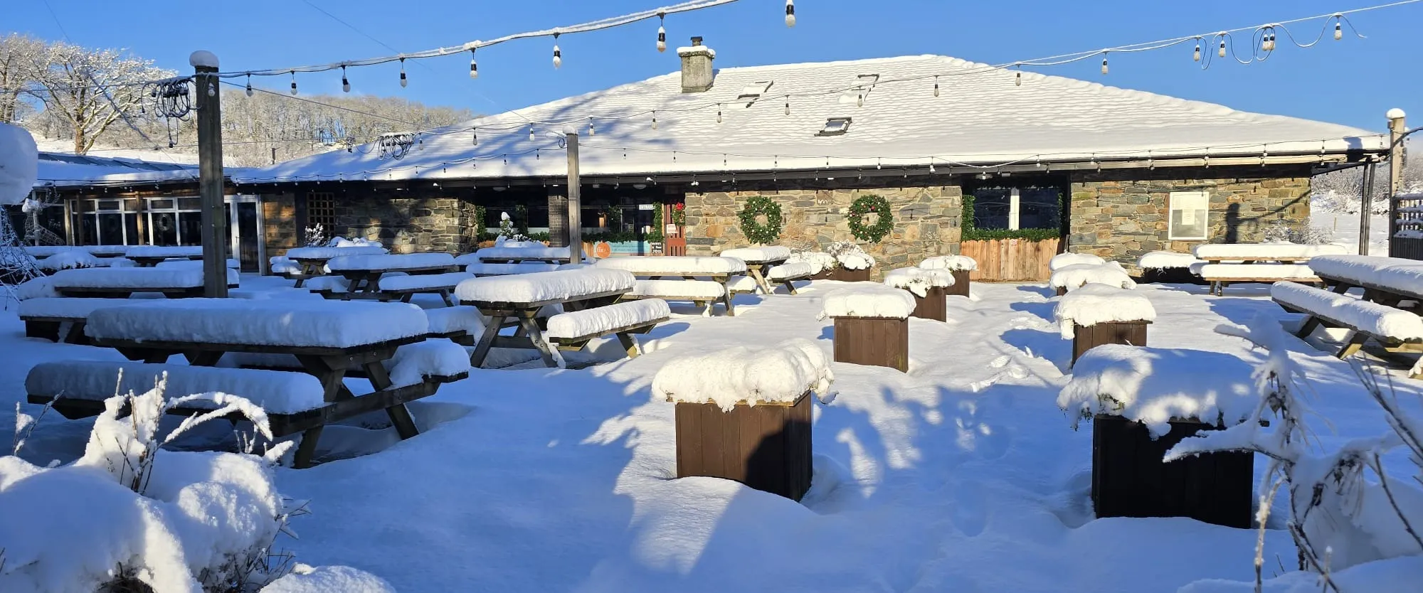 The beer garden and stone pub under snow, wreaths on the windows