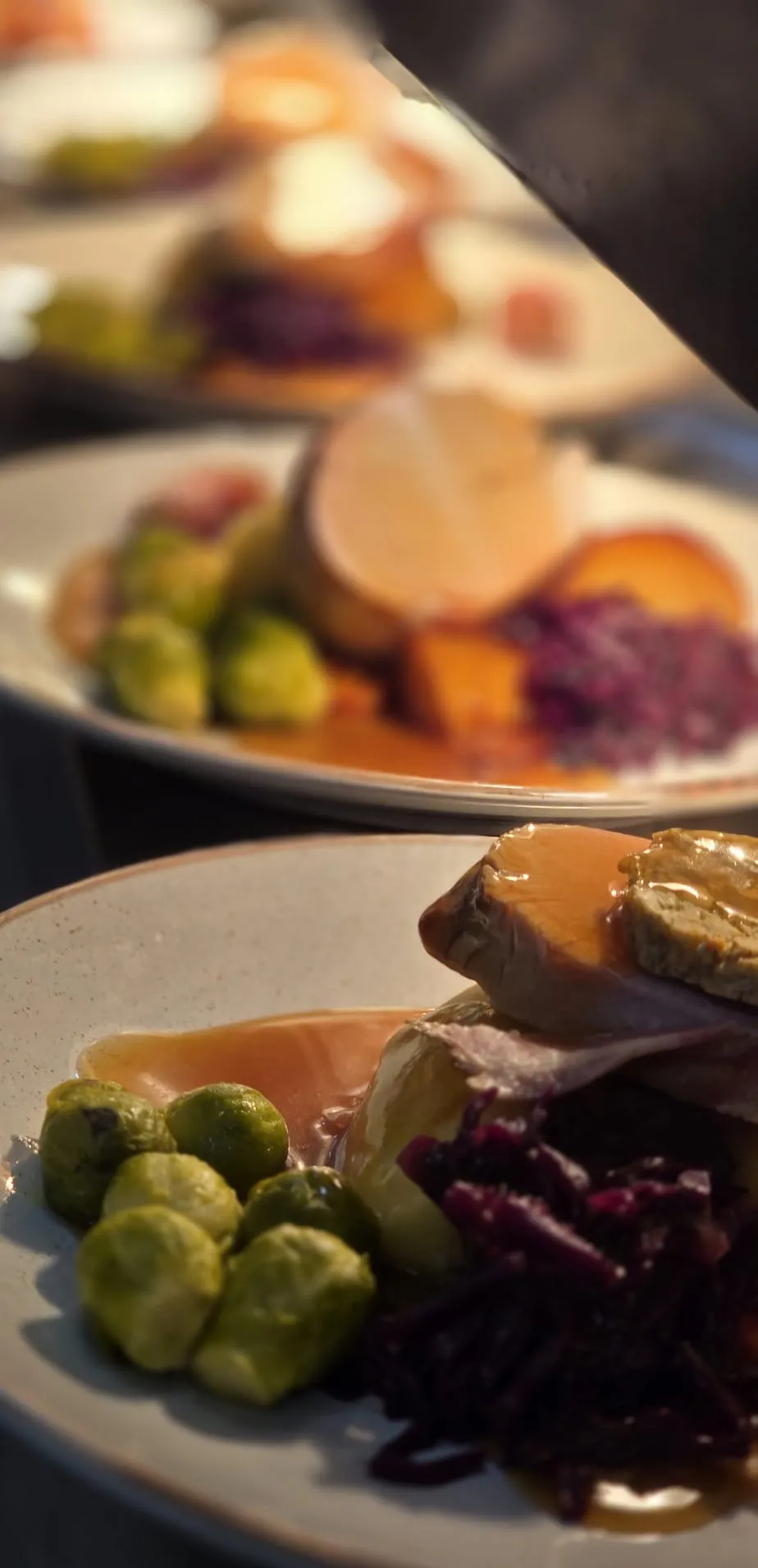 A row of plated Sunday roasts with sprouts, red cabbage and gravy