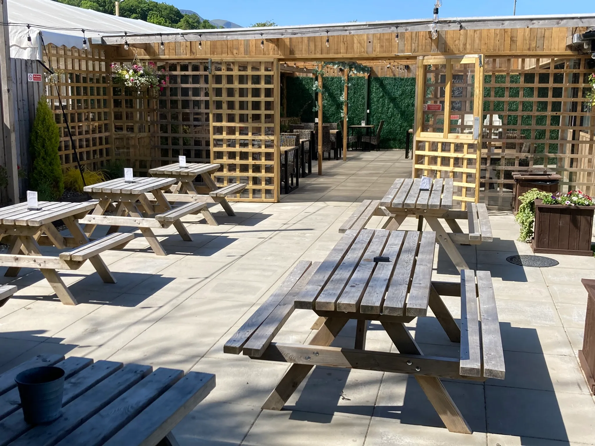 The covered terrace in the beer garden, with picnic tables and hanging baskets