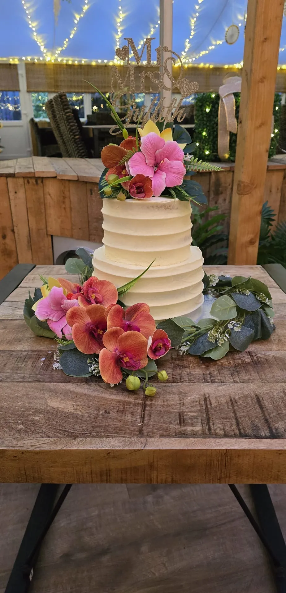 A two tier buttercream wedding cake with tropical flowers