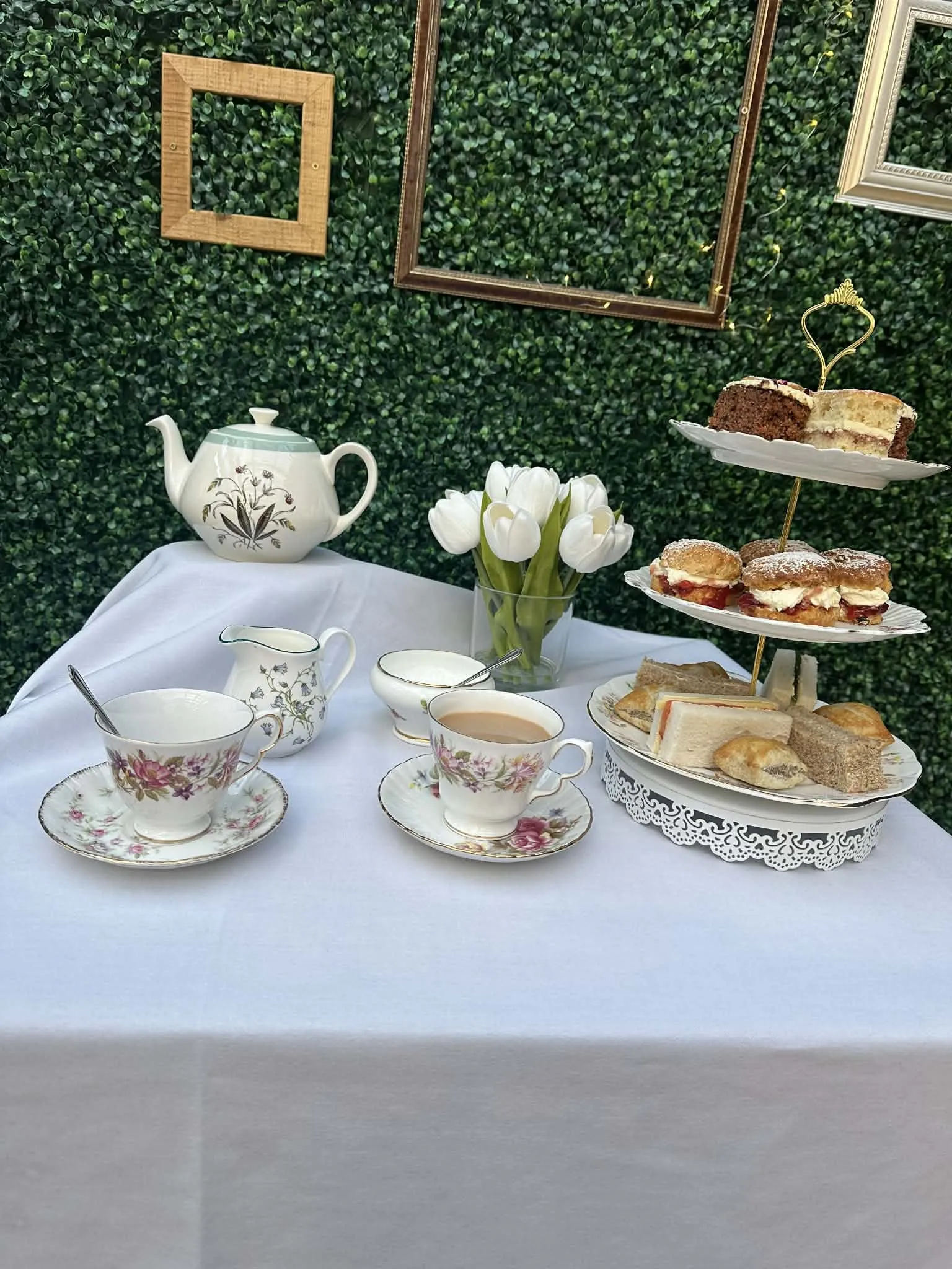 An afternoon tea table with vintage china, a teapot and white tulips