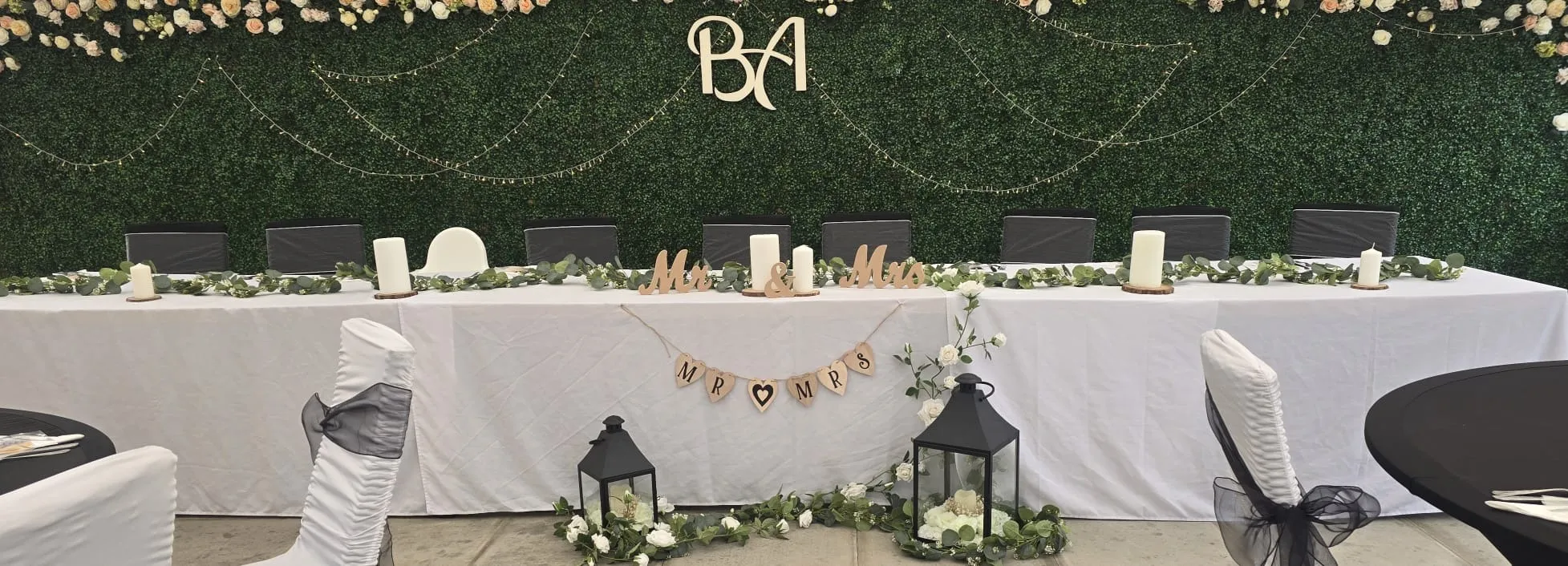 The top table with Mr and Mrs signs against the rose topped hedge wall